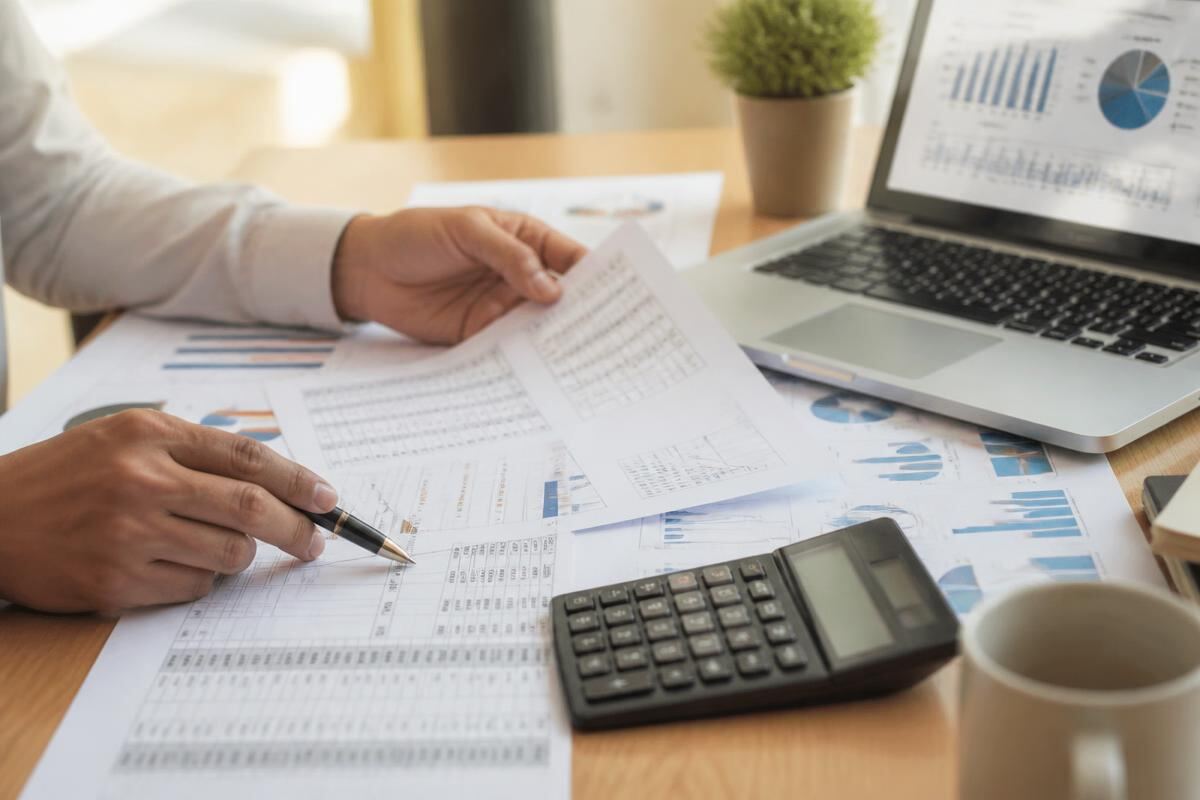 Bookkeeper reviewing monthly reconciliation reports and a laptop dashboard
